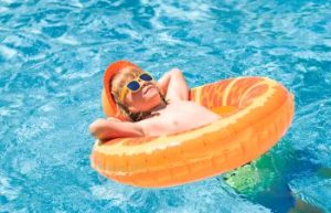 A happy relaxed child playing in a backyard swimming pool.