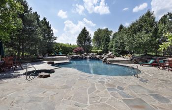 Outdoor swimming pool of a residential home with large stone deck.