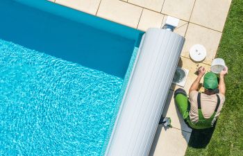 A professional technician cleaning swimming pool filter while performing seasonal pool inspection