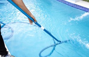 A technician cleaning and vacuuming the pool