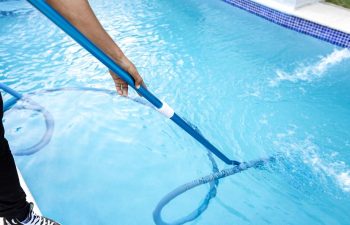 A technician cleaning and vacuuming the pool