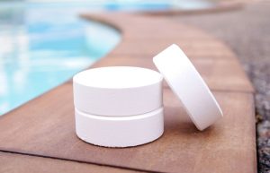 salt chlorine tablets lying on the edge of a backyard swimming pool